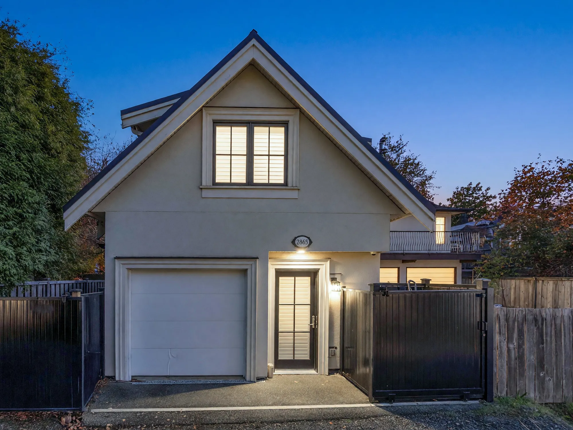 The laneway house at dusk, the upper window and the light over the door lit