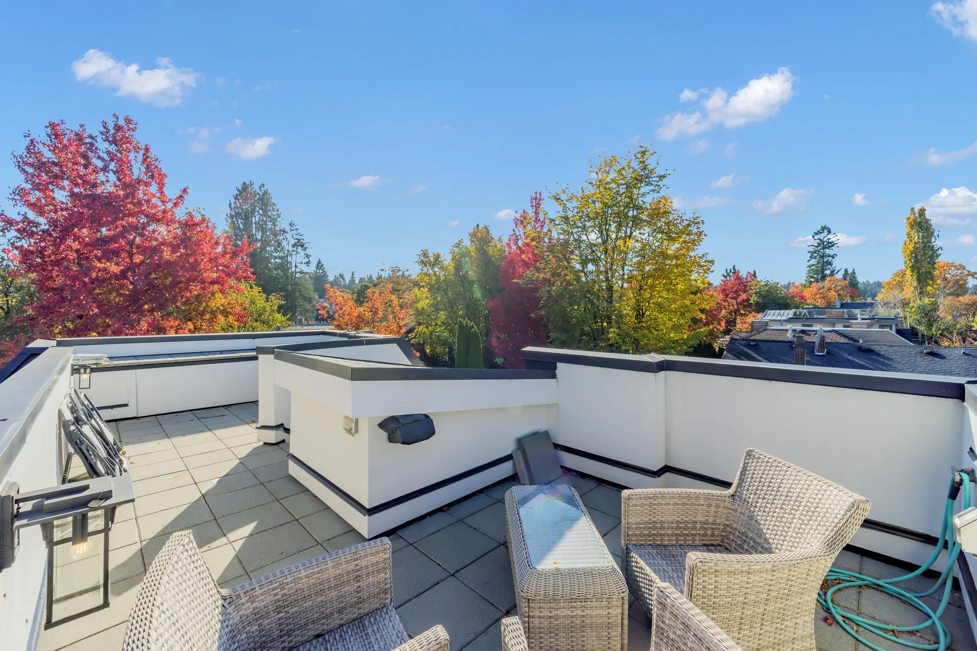 The roof deck from the far end: wicker seating, the parapet and the stair housing, a maple in red and gold