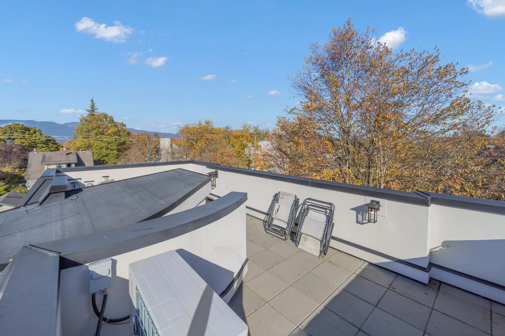 The view from the roof deck over the roofs of the neighbourhood to the mountains, the edge of the metal roof below